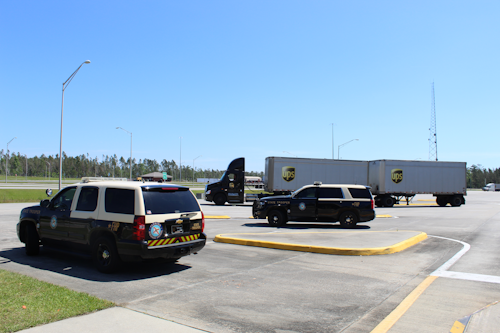 Two police vehicles and semi truck at inspection station